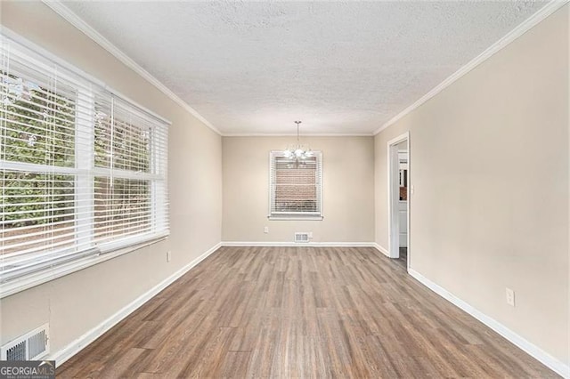 unfurnished dining area with crown molding, visible vents, wood finished floors, a chandelier, and baseboards