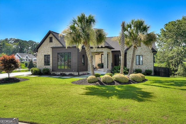 view of front of house with stone siding, fence, and a front lawn