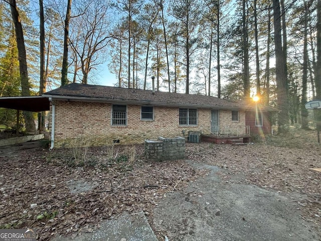 back of property with a carport, brick siding, and central air condition unit