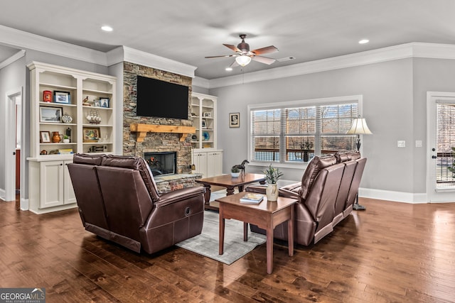 living area featuring a ceiling fan, dark wood-style flooring, ornamental molding, and a stone fireplace