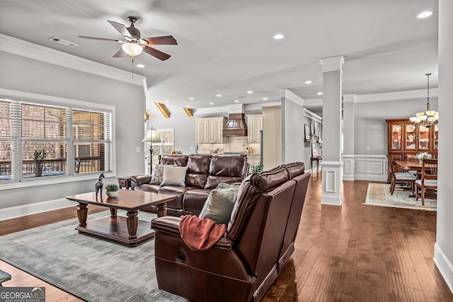 living room with ceiling fan with notable chandelier, decorative columns, visible vents, and crown molding