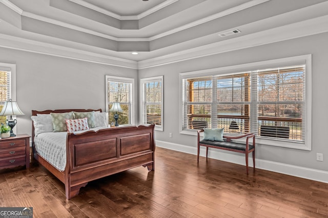 bedroom featuring a tray ceiling, hardwood / wood-style flooring, and visible vents