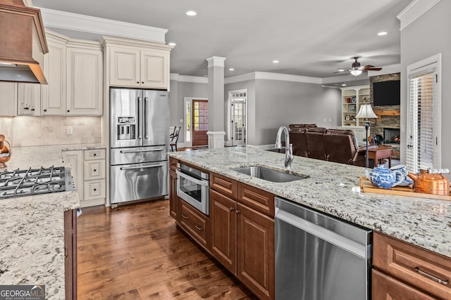 kitchen with decorative columns, custom range hood, dark wood-type flooring, stainless steel appliances, and a sink