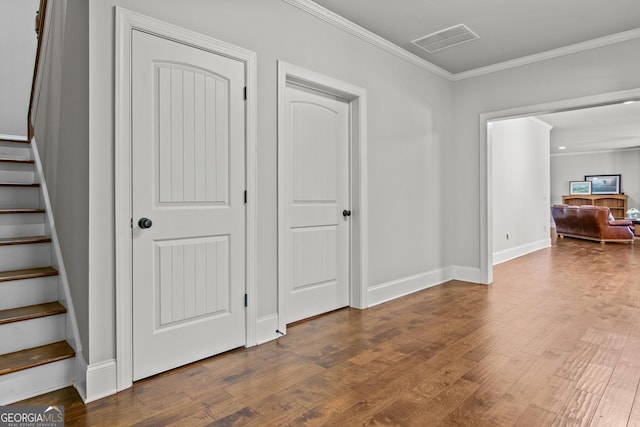 interior space featuring wood finished floors, visible vents, baseboards, stairway, and crown molding