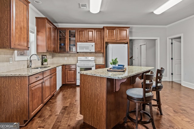 kitchen featuring white appliances, a sink, visible vents, and crown molding