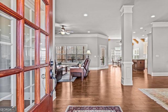 foyer with a ceiling fan, dark wood-style flooring, crown molding, and ornate columns