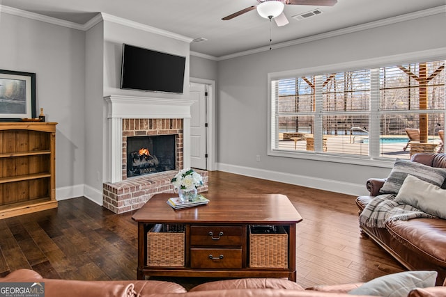 living room featuring visible vents, baseboards, ornamental molding, a brick fireplace, and dark wood finished floors