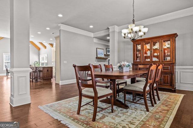 dining area with dark wood-type flooring, a notable chandelier, ornamental molding, and decorative columns