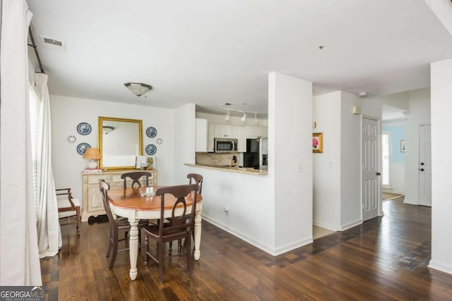 dining space with dark wood finished floors, visible vents, and baseboards