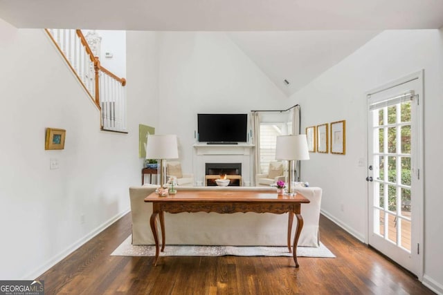 living room featuring high vaulted ceiling, a fireplace, baseboards, and wood finished floors