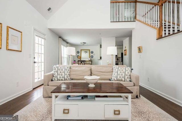 living room featuring high vaulted ceiling, visible vents, baseboards, and wood finished floors