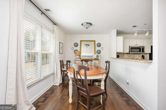 dining room with baseboards, visible vents, and dark wood finished floors