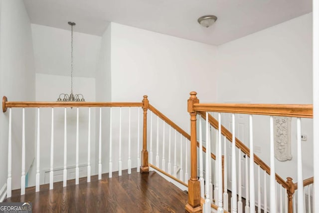 hall with a chandelier, wood finished floors, and an upstairs landing