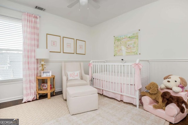 bedroom with ceiling fan, a crib, and visible vents