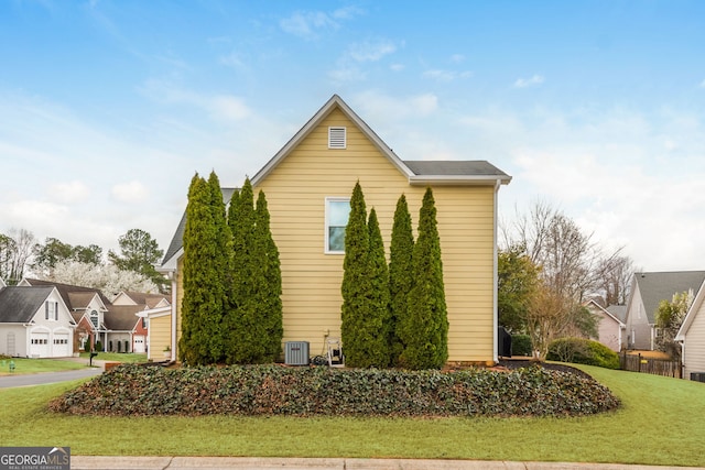 view of side of property featuring a residential view, central AC unit, and a yard