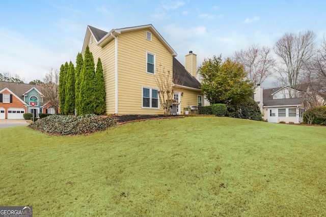 rear view of house featuring a yard and a chimney