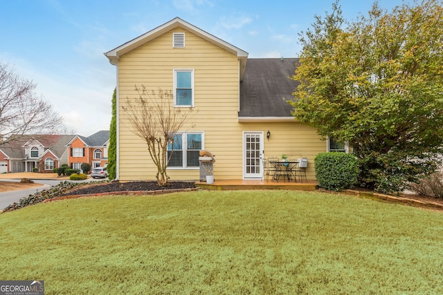 rear view of house with a shingled roof and a lawn