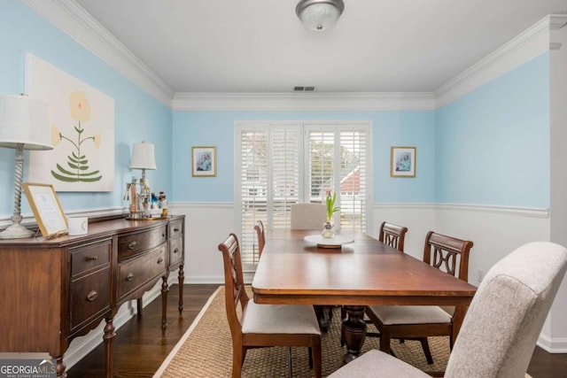 dining room featuring dark wood-style floors, baseboards, visible vents, and crown molding