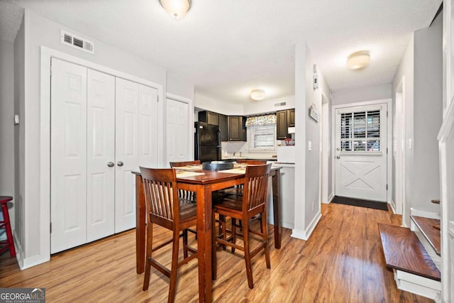 dining room featuring light wood-type flooring, visible vents, and baseboards