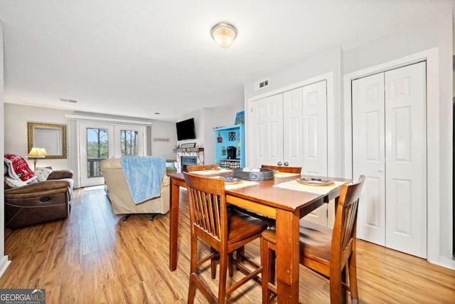 dining space with visible vents, a fireplace, and light wood-style flooring