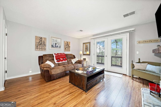 living room with light wood-style floors, baseboards, visible vents, and french doors