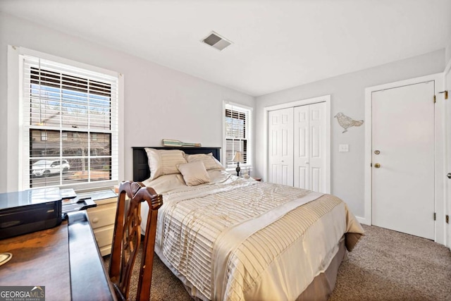 carpeted bedroom with a closet, visible vents, and multiple windows