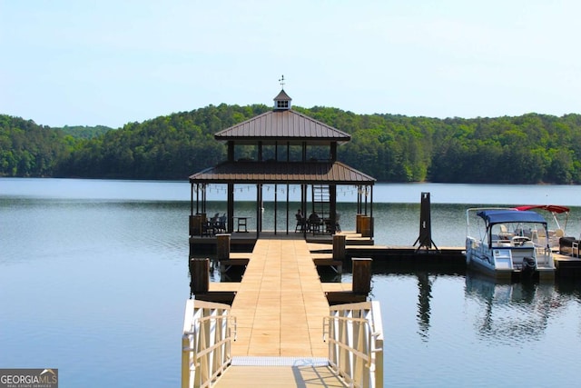 view of dock featuring a water view and a forest view