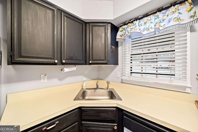 kitchen featuring dishwashing machine, light countertops, a sink, and dark brown cabinets