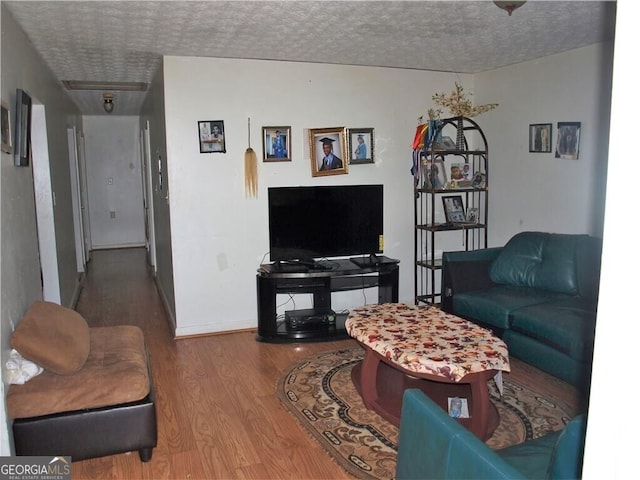 living room featuring a textured ceiling, baseboards, and wood finished floors