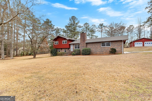 tri-level home with a front yard, a chimney, brick siding, a shingled roof, and a detached garage