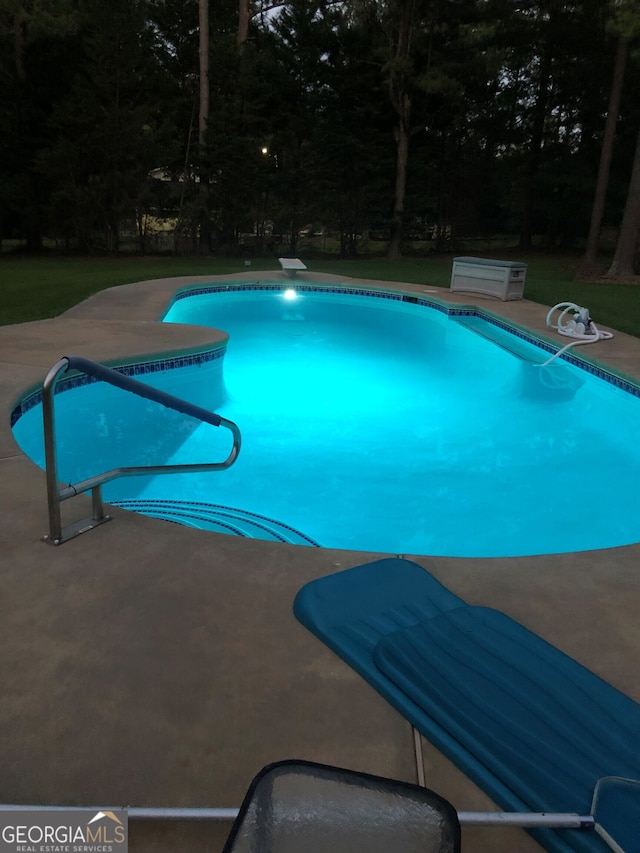 pool featuring a diving board and a patio area