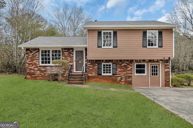 tri-level home with driveway, brick siding, a front lawn, and a shingled roof