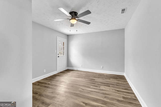 unfurnished room featuring ceiling fan, wood finished floors, visible vents, and baseboards