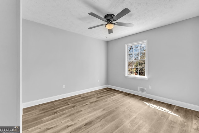 unfurnished room featuring a textured ceiling, ceiling fan, wood finished floors, visible vents, and baseboards