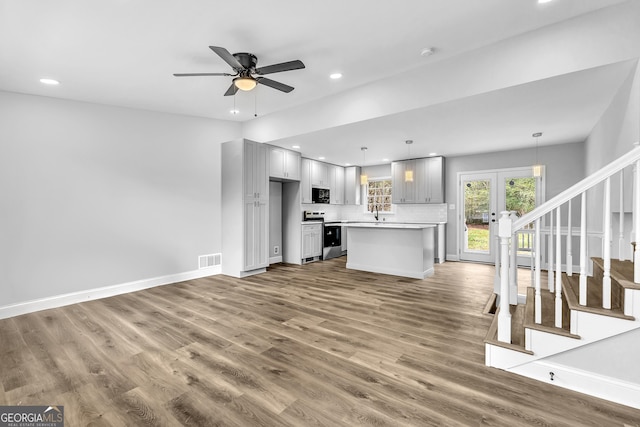 unfurnished living room featuring recessed lighting, wood finished floors, visible vents, baseboards, and stairway