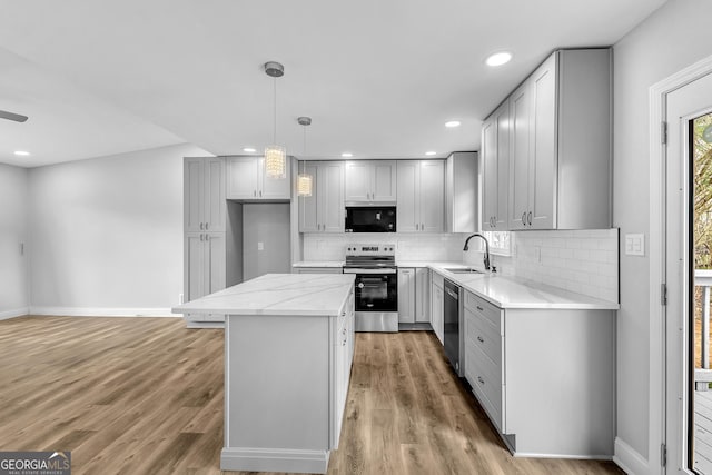 kitchen featuring appliances with stainless steel finishes, a kitchen island, a sink, and light wood-style floors