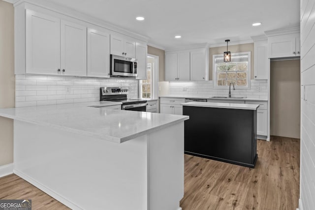 kitchen with a peninsula, a sink, white cabinetry, light wood-style floors, and appliances with stainless steel finishes