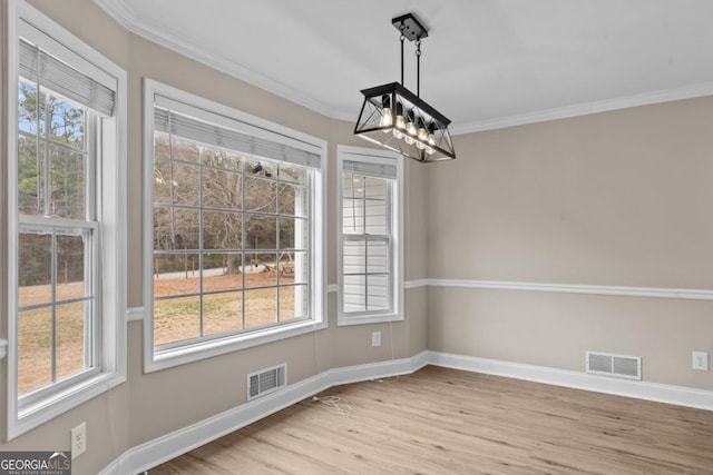 unfurnished dining area featuring baseboards, visible vents, wood finished floors, and ornamental molding