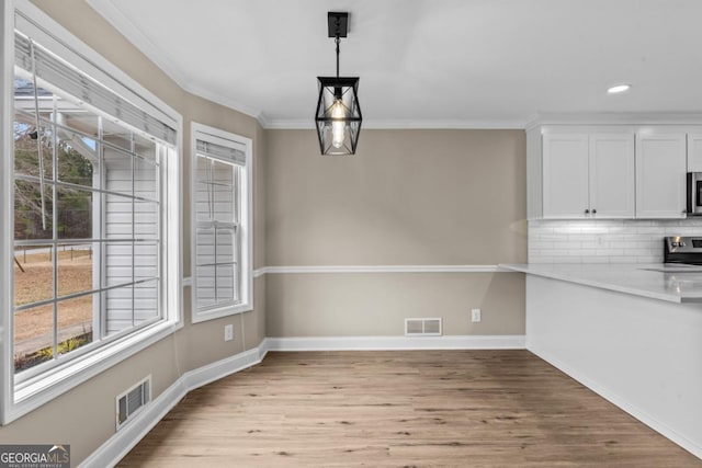 unfurnished dining area featuring ornamental molding, light wood-type flooring, and visible vents