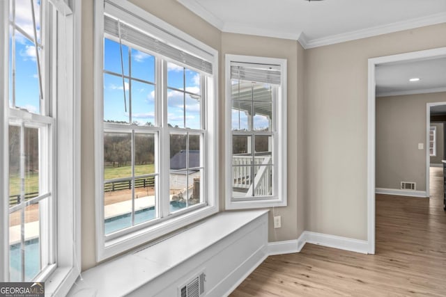 interior space with ornamental molding, wood finished floors, visible vents, and baseboards