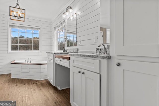 kitchen featuring dark wood-style floors, a sink, white cabinets, and wooden walls