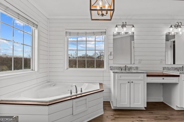 bathroom featuring vanity, ornamental molding, wood finished floors, and a bath