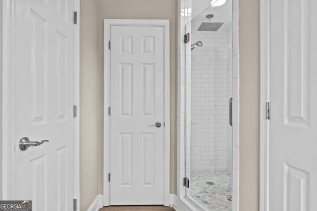 bathroom with a shower stall and baseboards