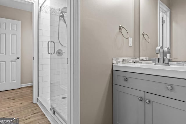 full bathroom with wood finished floors, a shower stall, and vanity