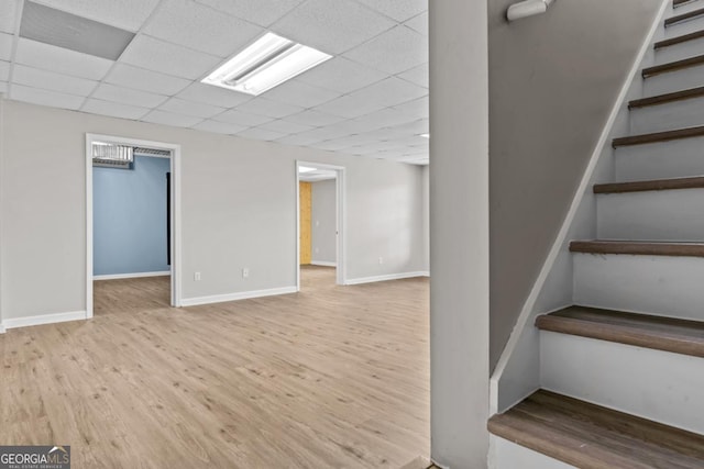 finished basement featuring stairs, baseboards, a drop ceiling, and wood finished floors