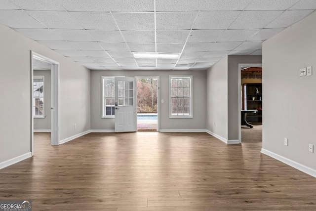 interior space featuring dark wood-type flooring, a paneled ceiling, and baseboards