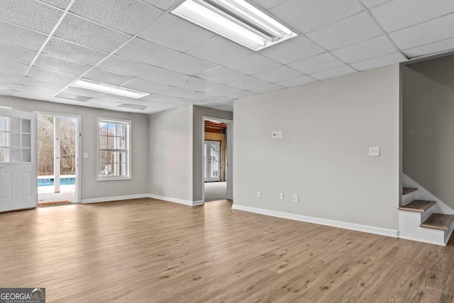 spare room featuring stairway, a drop ceiling, wood finished floors, and baseboards