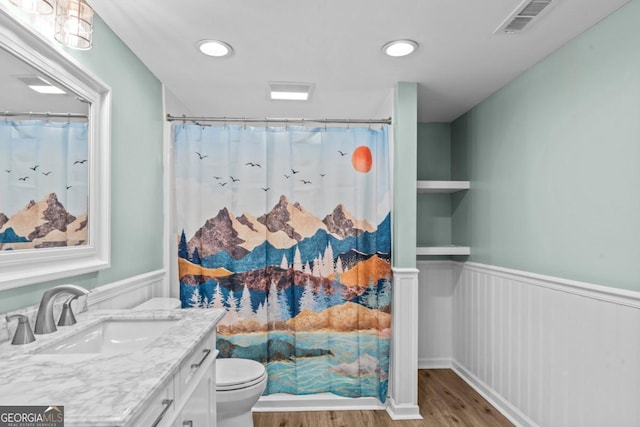 full bathroom with toilet, wood finished floors, vanity, visible vents, and wainscoting