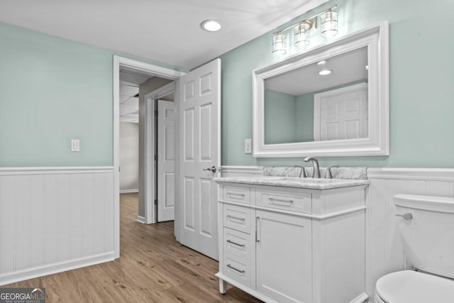 bathroom featuring vanity, wainscoting, wood finished floors, and toilet