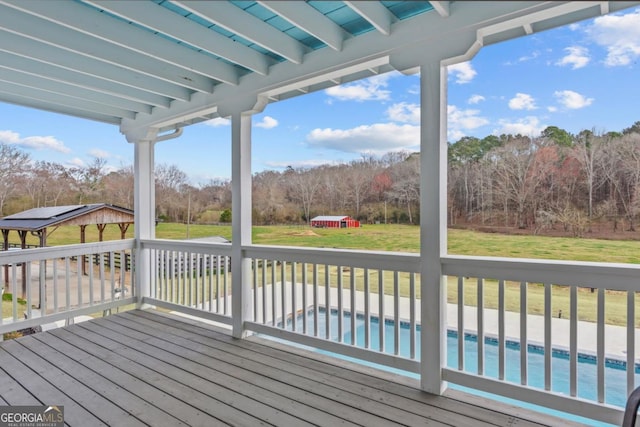 deck with an outbuilding, a lawn, and an outdoor pool